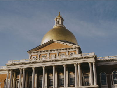 The exterior of the Massachusetts State House on a clear, sunny day.